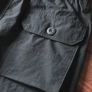 Dettaglio ravvicinato della tasca cargo con bottone sui pantaloni outdoor da uomo