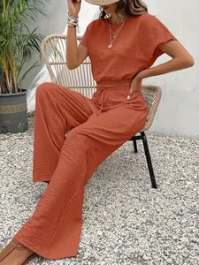 Elegante roestoranje tweedelige set met crop top en broek met wijde pijpen op een model