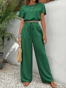Elegant groen tweedelig pak met getextureerde cropped top en broek met wijde pijpen.