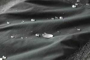 Detailed close-up view of waterproof softshell fabric with water droplets on surface