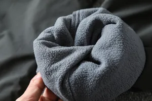 Close-up view of the thick grey fleece lining in men's winter outdoor softshell pants for warmth