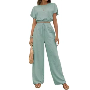 Elegante saliegroene tweedelige set met crop top met korte mouwen en broek met wijde pijpen