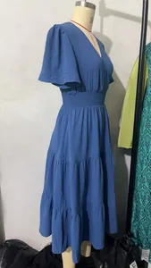 Vue latérale d'une robe mi-longue à volants bleue avec taille smockée sur un mannequin.