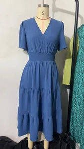 Détail d'une robe mi-longue bleue à col en V avec taille smockée et jupe à étages