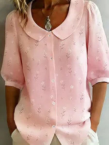 Close-up view of a pink floral Peter Pan collar blouse with small white buttons