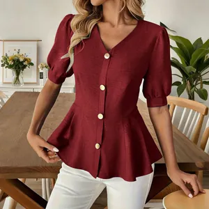 Detail of elegant burgundy V-neck blouse featuring puff sleeves and gold buttons