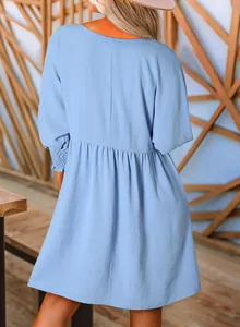 Vue arrière détaillée d'une robe bleu clair à col rond avec smocks et design à étages.