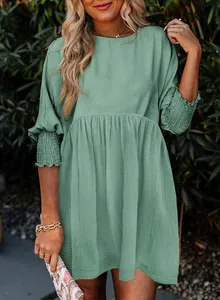 Détail d'une robe décontractée vert sauge avec col rond et poignets froncés chic.