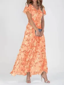A full-length view of an orange floral chiffon maxi dress featuring elegant flutter sleeves