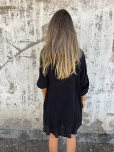 Back view of a loose black long-sleeved crinkled cotton linen shirt shown on a model
