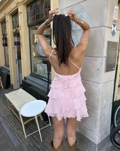 Achteraanzicht van een roze mini-jurk met ruches en open rug in een zomerse straat