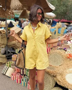Detail of a vibrant yellow short sleeve summer romper jumpsuit worn in a market setting