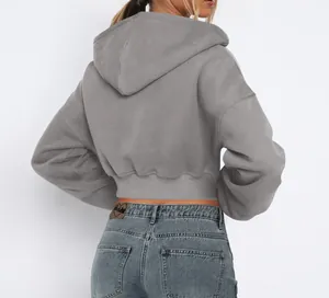 Back view of a grey cropped fleece hoodie with ribbed waist paired with blue jeans
