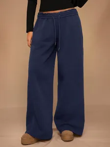 Detalle de pantalón de chándal de forro polar azul marino con pernera ancha y cordón.