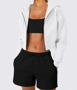 Close-up detail of a stylish white cropped zip-up hoodie worn over a black sports bra