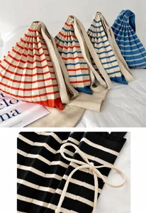 Close-up of pleated knitted fabric texture on stylish colorful striped crossbody bags.