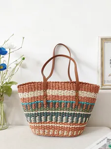 Large rainbow striped hand-woven straw tote bag with brown leather straps for beach vacation.