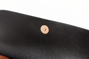 Vue macro détaillée du bouton pression magnétique doré sur un sac cabas en cuir noir