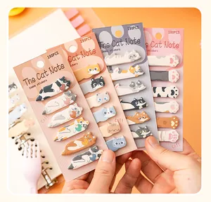 Three sets of cute cartoon cat index stickers held against a spiral notebook background