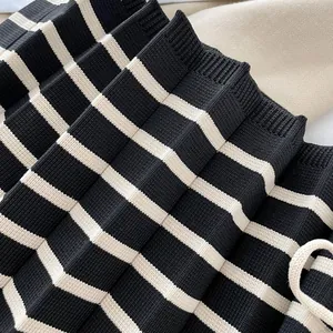 Close-up of a pleated knitted crossbody bag with black and beige stripes