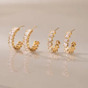 Close-up of gold-plated C-shaped earrings with sparkling cubic zirconia stones