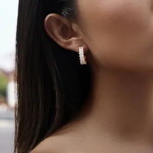 Close-up of a gold C-shaped earring with marquise zircons worn on a model's ear.