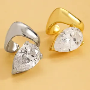 Macro detail of pear-cut cubic zirconia twisted ear cuffs in gold and silver finishes.