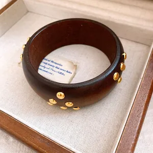 Nahaufnahme eines Retro-Holzarmreifs mit Goldnietenverzierungen in einer edlen Holzbox