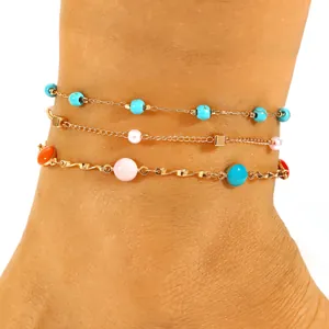 Close-up of layered stainless steel anklets with colorful beads for beach vacation style.