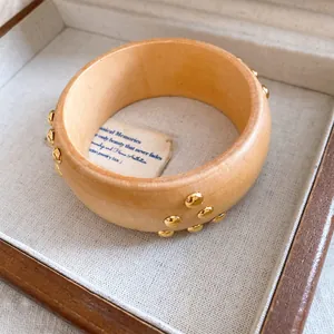 Λεπτομερής άποψη vintage ξύλινου βραχιολιού με χρυσά τρουκς σε ένα κουτί κοσμημάτων