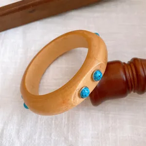 Detaillierte Ansicht eines Vintage-Holzarmreifs mit blauen Steineinlagen im Boho-Stil