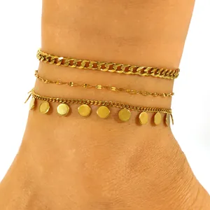 Set of triple-layered golden stainless steel anklets with disc charms on an ankle.