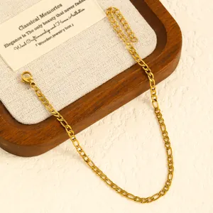 Close-up of elegant gold-finished Figaro chain anklet on a classic wooden jewelry tray.