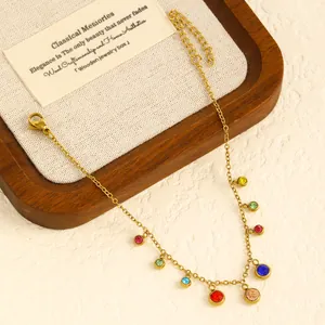 Detail view of a golden stainless steel anklet with vibrant multi-colored gemstone charms