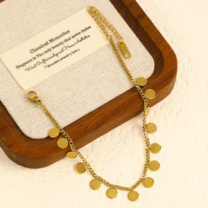 Close-up detail of a gold stainless steel anklet with dangling round disc charms for beach style