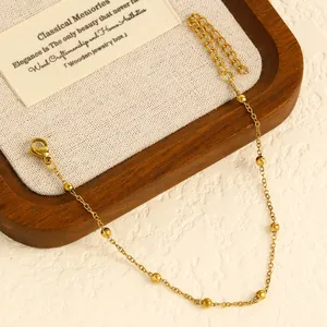 High-quality detail of a gold stainless steel beaded anklet on a premium wooden tray