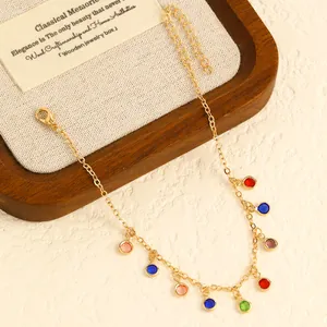 Close-up of a gold stainless steel anklet with vibrant colorful round drop charms.