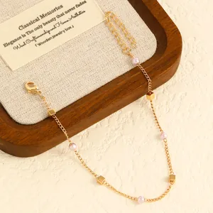 Detailed view of a gold-toned anklet featuring delicate pink pearls and small cubes