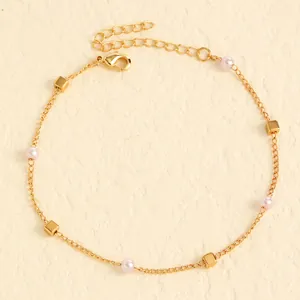 Close-up of gold-plated stainless steel anklet with pink pearls and cubic beads.
