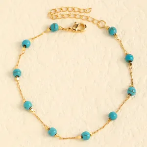 Detailed macro view of a gold chain anklet featuring turquoise beads and lobster clasp.