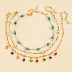 Close-up of layered stainless steel anklet set with colorful stones and turquoise beads