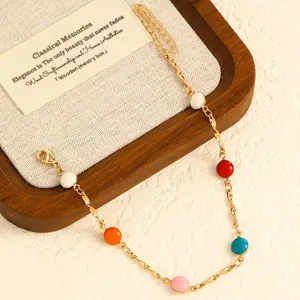 Detailed macro view of colorful stainless steel drip oil bead anklet on a wooden display