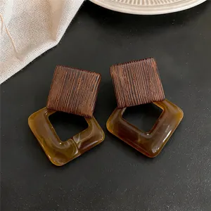 Detail view of retro wood and amber resin diamond drop earrings on black background