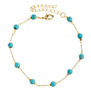 Close-up detail of a gold stainless steel anklet with turquoise beads for beach vacation style