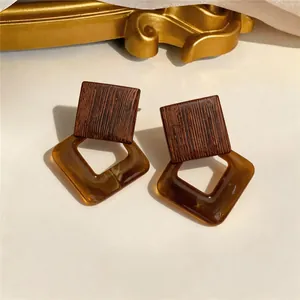 Close-up detail of retro style wood and amber resin diamond-shaped drop earrings.