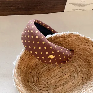 Close-up of a stylish brown polka dot padded headband displayed in a woven basket