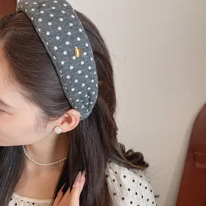 Side view of a padded grey fabric headband with white polka dots worn by a model