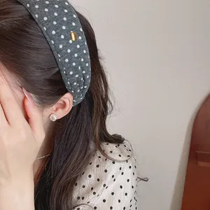 Close-up of grey polka dot wide fabric headband with gold accent worn by model
