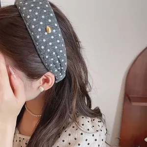 Detailed close-up of a grey polka dot fabric wide headband with a gold metal accent.