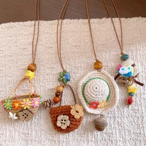 Close-up of four handmade pastoral style crochet and wood necklaces on textured mat